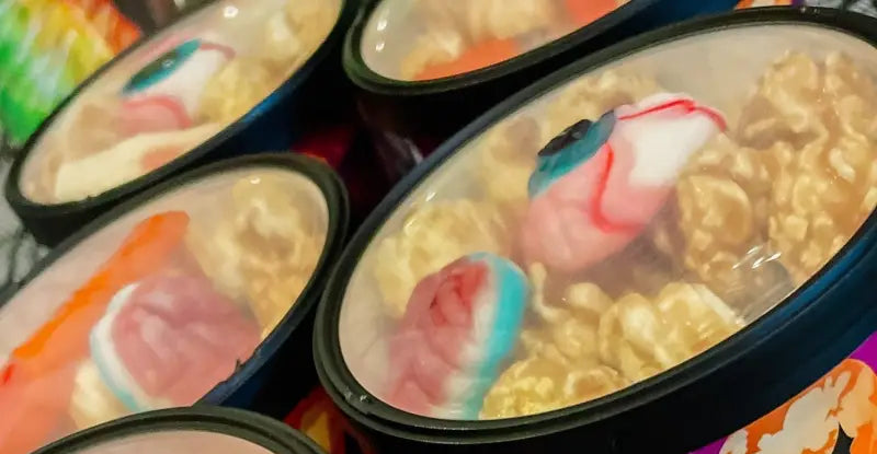 Gummy candy-topped popcorn in clear, lidded containers.