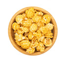 A wooden bowl filled with golden, crispy popcorn kernels.