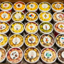 An advent calendar box filled with twenty-four individual tubs of gourmet popcorn, each with a unique Christmas-themed sticker.