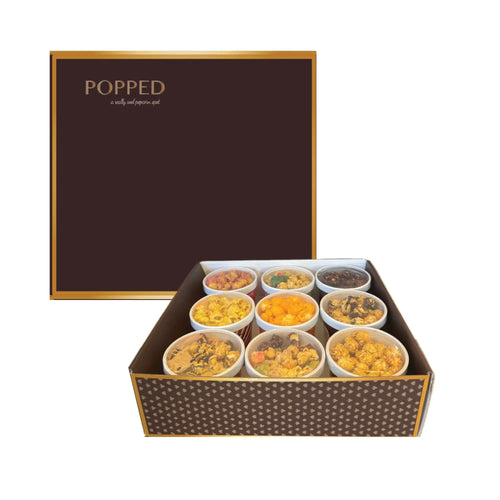 Brown and gold rectangular box filled with assorted snacks, likely a gourmet gift set.