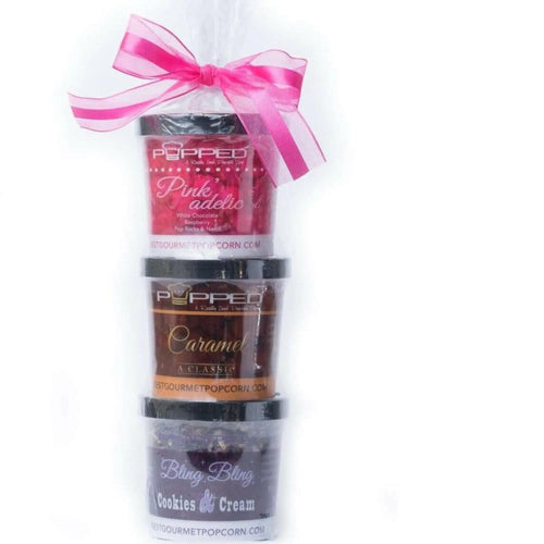 A stack of three gourmet popcorn containers tied with a pink ribbon.