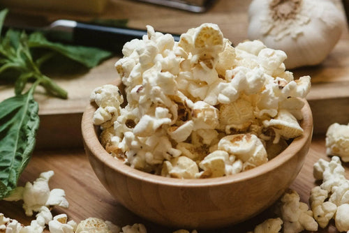 A wooden bowl filled with fluffy, white, savory popcorn.