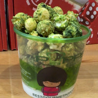 Green-tinted popcorn in a clear plastic cup with a green rim and cartoon character design.