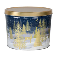 A festive navy blue metal tin with a gold lid, featuring an illustrated winter scene of golden pine trees and a deer under a starry night sky.
