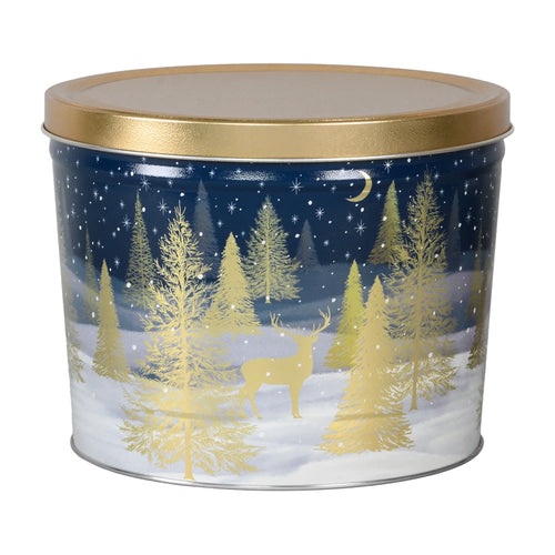 A festive navy blue metal tin with a gold lid, featuring an illustrated winter scene of golden pine trees and a deer under a starry night sky.