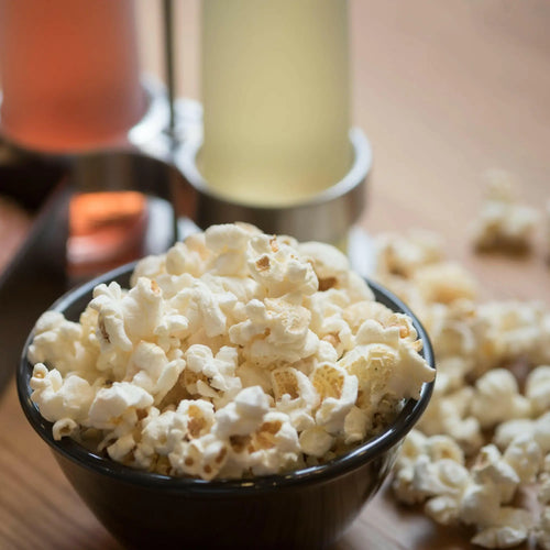Freshly popped, fluffy white popcorn in a black bowl.