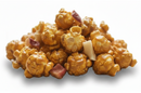 A pile of caramel popcorn mixed with pieces of dried apple pieces, isolated on a white background.