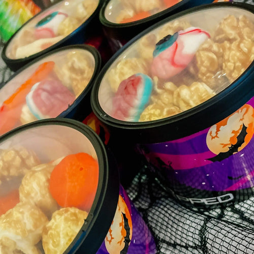Gummy candy-topped popcorn in clear, lidded containers.