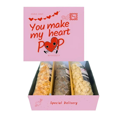 Pink gift box with you make my heart pop design holding three wrapped chocolates in a gourmet popcorn sampler gift
